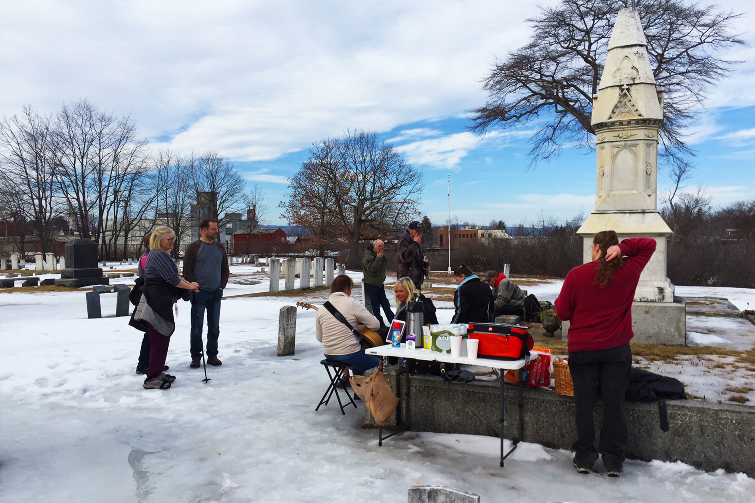 Photo of table with coffee and people congregating in the cemetery, Laconia, NH during winter.